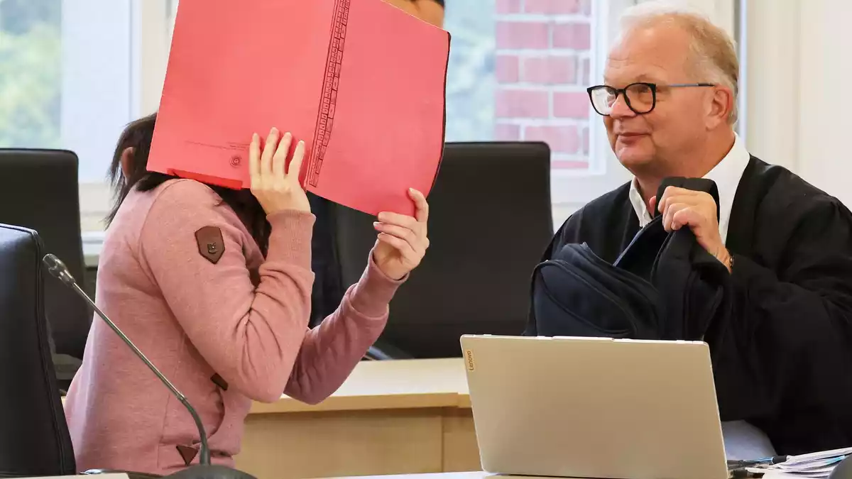 Die Angeklagte betritt den Gerichtssaal seit Monaten mit Fußfesseln und einem Aktendeckel vor dem Gesicht.  - Bild: Bernd Wüstneck/dpa
