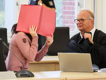 Die Angeklagte betritt den Gerichtssaal seit Monaten mit Fußfesseln und einem Aktendeckel vor dem Gesicht.  - Foto: Bernd Wüstneck/dpa