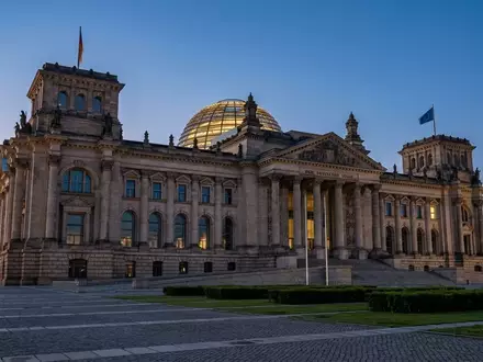 Die Architektur des Reichstagsgebäudes in Berlin während der Dämmerung mit Fokus auf die Steinfassade und die Glaskuppel. - Foto: über boerse-global.de