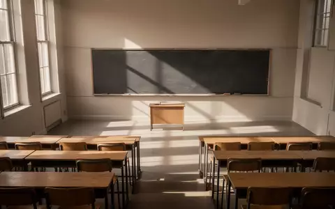 Ein leerer, minimalistischer Hörsaal mit hölzernen Tischen und einer großen, leeren Schiefertafel bei natürlichem Lichteinfall. - Foto: über boerse-global.de