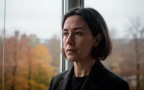 Eine Person steht an einem Fenster an einem bewölkten Herbsttag, während das Tageslicht ihr Gesicht sanft beleuchtet. - Foto: über boerse-global.de