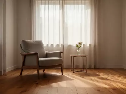 Ein heller, minimalistisch eingerichteter Wohnraum mit einem Sessel am Fenster und einer einzelnen Vase auf einem Beistelltisch. - Foto: über boerse-global.de