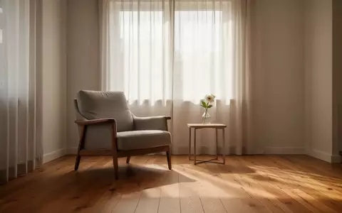Ein heller, minimalistisch eingerichteter Wohnraum mit einem Sessel am Fenster und einer einzelnen Vase auf einem Beistelltisch. - Foto: über boerse-global.de