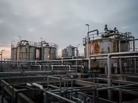 Industrielle Kläranlage mit großen Metalltanks und Rohrleitungssystemen bei Dämmerung. - Foto: über boerse-global.de