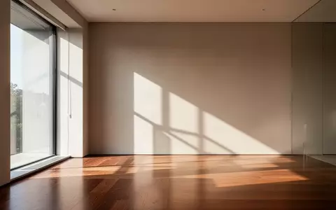 Ein minimalistischer, heller Innenraum mit klaren Linien und natürlichem Licht, das geometrische Schatten auf eine Wand wirft. - Foto: über boerse-global.de