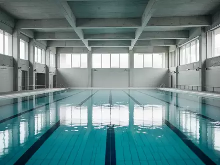 Ein leeres, modernes Hallenbad mit klarem blauem Wasser und architektonischen Details bei natürlichem Tageslicht. - Foto: über boerse-global.de