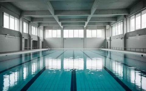 Ein leeres, modernes Hallenbad mit klarem blauem Wasser und architektonischen Details bei natürlichem Tageslicht. - Foto: über boerse-global.de