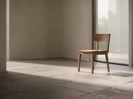 Ein minimalistischer, lichtdurchfluteter Raum mit einem leeren Holzstuhl, der Ruhe und finanzielle Stabilität symbolisiert. - Foto: über boerse-global.de