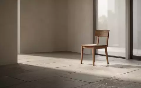 Ein minimalistischer, lichtdurchfluteter Raum mit einem leeren Holzstuhl, der Ruhe und finanzielle Stabilität symbolisiert. - Foto: über boerse-global.de