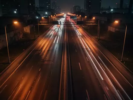 Eine nächtliche, schwach beleuchtete Autobahn in einer städtischen Umgebung mit verschwommenen Lichtspuren des Verkehrs. - Foto: über boerse-global.de