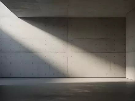 Ein minimalistischer, leerer Raum mit strukturierten Betonwänden und weichem Lichteinfall, der eine sterile und isolierte Atmosphäre schafft. - Foto: über boerse-global.de