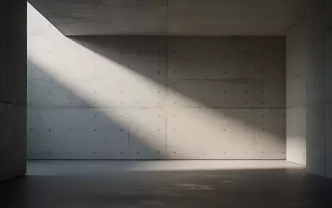 Ein minimalistischer, leerer Raum mit strukturierten BetonwĂ€nden und weichem Lichteinfall, der eine sterile und isolierte AtmosphĂ€re schafft. - Foto: ĂŒber boerse-global.de