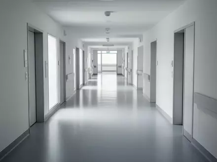 Ein minimalistischer, leerer Flur in einem modernen Krankenhaus mit hellen Wänden und reflektierenden Böden. - Foto: über boerse-global.de