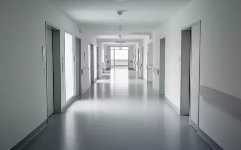 Ein minimalistischer, leerer Flur in einem modernen Krankenhaus mit hellen Wänden und reflektierenden Böden. - Foto: über boerse-global.de