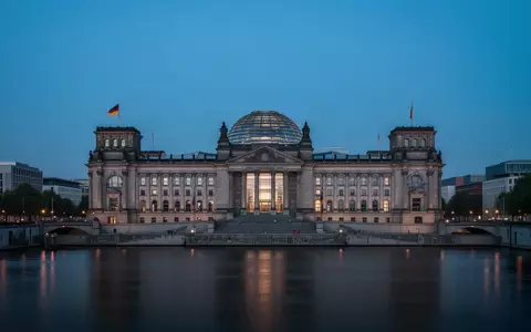 Das Reichstagsgebäude in Berlin bei Dämmerung, gesehen von der anderen Seite der Spree. - Foto: über boerse-global.de