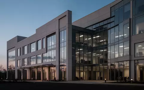 Ein modernes, minimalistisches Bürogebäude in der Dämmerung, das die Architektur und das Arbeitsumfeld betont. - Foto: über boerse-global.de