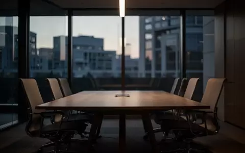 Ein leerer, ruhiger Konferenzraum in einem Bürogebäude bei Dämmerung, der eine Atmosphäre von Stille und Rückzug vermittelt. - Foto: über boerse-global.de