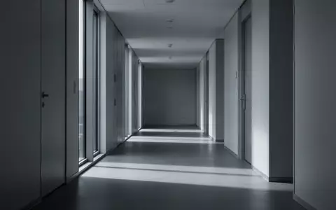 Ein leerer, minimalistischer Flur in einem modernen Bürogebäude mit langen Schatten und kühlem Tageslicht. - Foto: über boerse-global.de