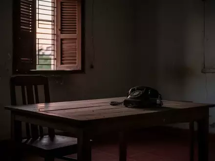 Ein schlichter, leerer Raum mit einem alten Telefon auf einem Holztisch bei Dämmerlicht. - Foto: über boerse-global.de