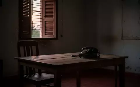 Ein schlichter, leerer Raum mit einem alten Telefon auf einem Holztisch bei Dämmerlicht. - Foto: über boerse-global.de