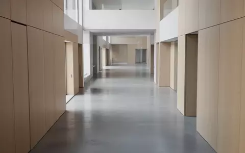 Ein minimalistischer, leerer Flur in einem modernen Verwaltungsgebäude mit klaren architektonischen Linien und Tageslicht. - Foto: über boerse-global.de