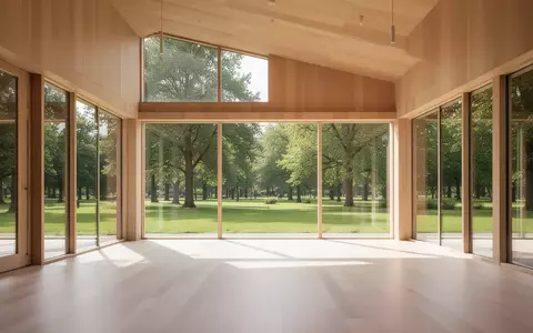 Heller, minimalistischer Bewegungsraum mit Holzboden und großen Fenstern mit Blick auf einen grünen Park. - Foto: über boerse-global.de