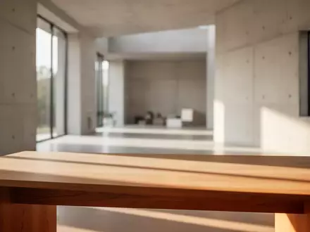 Ein minimalistischer Arbeitsplatz mit einem leeren Holztisch und weichem Tageslicht in einem modernen, hellen Innenraum. - Foto: über boerse-global.de
