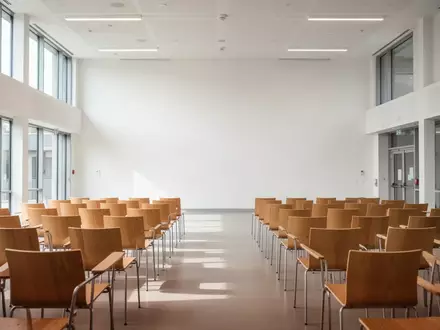 Ein heller Gemeindesaal mit leeren Stühlen in einer brandenburgischen Kommune. - Foto: über boerse-global.de