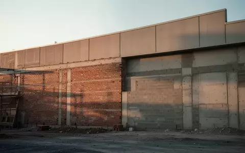 Ein unbewohntes GewerbegebĂ€ude mit einer Ziegelwand und einer Dachkante bei Tageslicht. - Foto: ĂŒber boerse-global.de