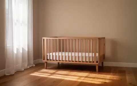 Ein ruhiges, minimalistisch eingerichtetes Kinderzimmer mit einem leeren Holzbett und weichem Tageslichteinfall. - Foto: über boerse-global.de