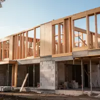 Eine moderne Baustelle mit Holzrahmenbau und Mauerwerk unter freiem Himmel. - Foto: über boerse-global.de