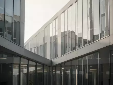 Moderne, minimalistische Fassade eines Bürogebäudes aus Glas und Beton bei Tageslicht. - Foto: über boerse-global.de