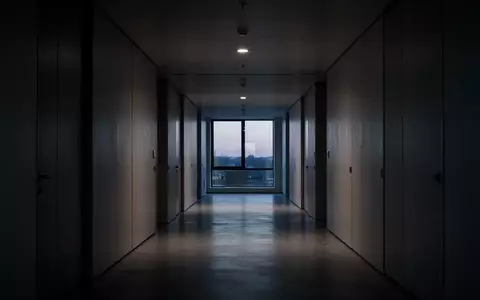 Ein leerer, minimalistisch gestalteter Büroflur im Dämmerlicht, der eine Atmosphäre von Isolation und struktureller Strenge vermittelt. - Foto: über boerse-global.de