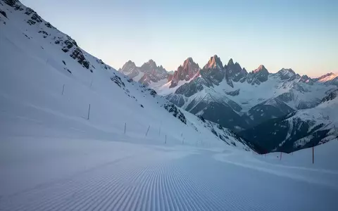 Verschneiter, präparierter Pistenabschnitt in einem alpinen Bergmassiv bei Tagesanbruch. - Foto: über boerse-global.de