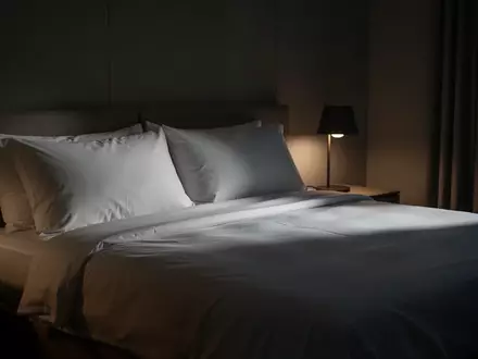 Ein minimalistisch eingerichtetes, in sanftes Licht getauchtes Schlafzimmer bei Nacht. - Foto: über boerse-global.de