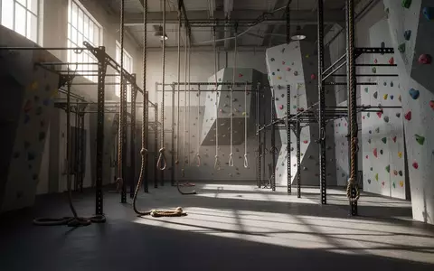 Leere Trainingshalle für Hindernisläufe mit Kletterwänden und Stahlkonstruktionen in natürlichem Licht. - Foto: über boerse-global.de