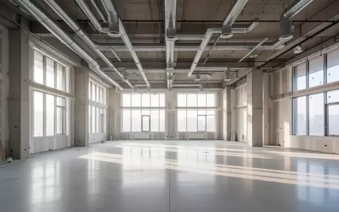 Ein heller, leerer Industrieraum mit hohen Decken und poliertem Betonboden während einer Renovierung. - Foto: über boerse-global.de