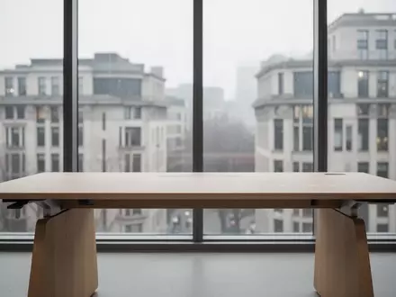 Ein minimalistischer, leerer Schreibtisch aus hellem Holz vor einem großen Fenster mit Blick auf eine Stadtlandschaft. - Foto: über boerse-global.de