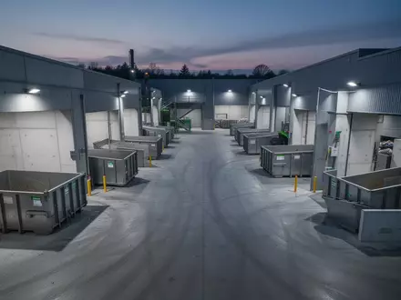 Ein sauberer, organisierter Recyclinghof mit leeren Metallcontainern und Betonboxen in der Dämmerung. - Foto: über boerse-global.de