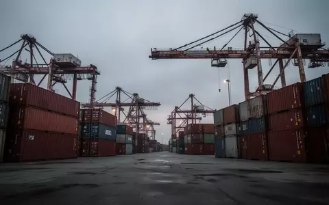 Ein stiller Industriehafen mit leeren Containern und Kränen unter einem bewölkten Himmel, der die wirtschaftliche Belastung symbolisiert. - Foto: über boerse-global.de
