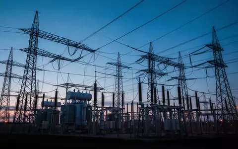Ein Hochspannungsumspannwerk mit massiven Stahltürmen und Transformatoren in der Abenddämmerung. - Foto: über boerse-global.de