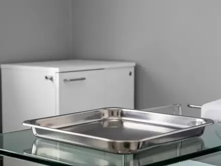 Ein minimalistischer, steriler Behandlungsraum mit einem leeren Edelstahltablett in einem neutralen, hellen Ambiente. - Foto: über boerse-global.de