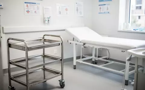 Ein heller, leerer Behandlungsraum in einer Kinderarztpraxis mit Untersuchungsliege und medizinischem Rollwagen. - Foto: über boerse-global.de