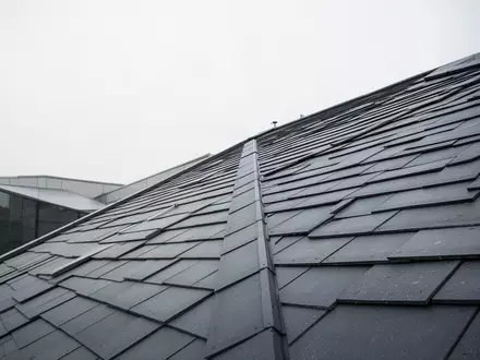 Ein steil geneigtes, mit Dachziegeln gedecktes Schrägdach aus einer erhöhten Perspektive bei bewölktem Himmel. - Foto: über boerse-global.de