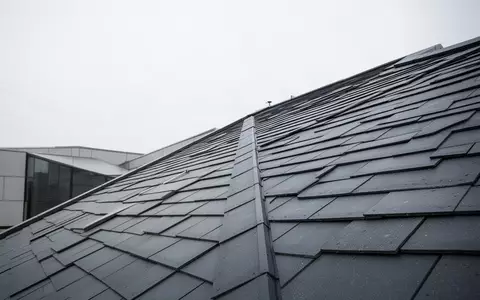 Ein steil geneigtes, mit Dachziegeln gedecktes Schrägdach aus einer erhöhten Perspektive bei bewölktem Himmel. - Foto: über boerse-global.de