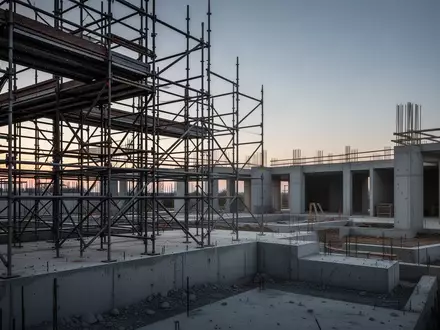 Eine leere Baustelle mit Stahlgerüsten und Betonfundamenten in der Abenddämmerung. - Foto: über boerse-global.de