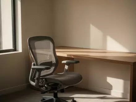 Ein minimalistisch gestalteter, sonnendurchfluteter Arbeitsplatz mit einem leeren ergonomischen Bürostuhl und einem sauberen Schreibtisch. - Foto: über boerse-global.de