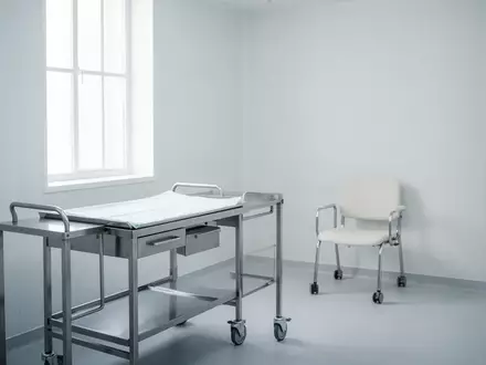 Ein steriler, minimalistischer Behandlungsraum in einer medizinischen Praxis mit einem leeren Metallwagen. - Foto: über boerse-global.de
