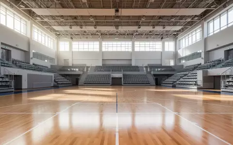 Eine leere, moderne Sporthalle mit hellem Holzboden und TribĂĽnen bei natĂĽrlichem Tageslicht. - Foto: ĂĽber boerse-global.de