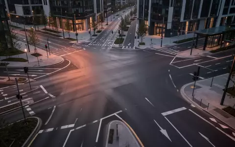 Eine leere, moderne städtische Straßenkreuzung bei Dämmerung mit klaren Fahrbahnmarkierungen und weichem Licht. - Foto: über boerse-global.de